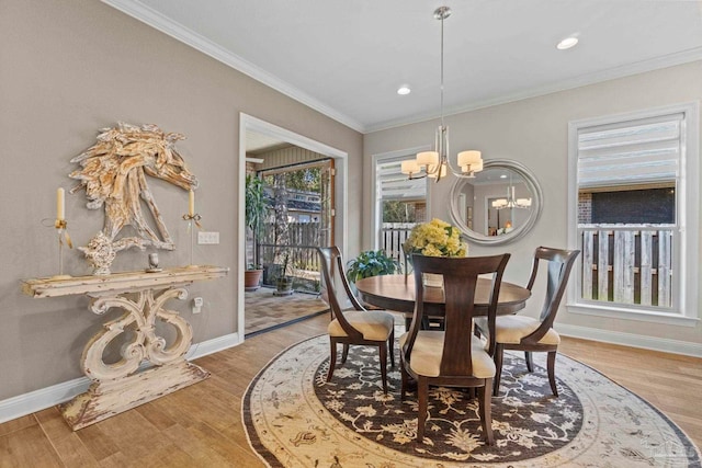 dining space with a chandelier, crown molding, baseboards, and wood finished floors