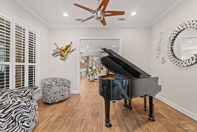 sitting room featuring baseboards, visible vents, wood finished floors, and ornamental molding