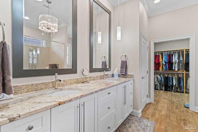 full bathroom featuring crown molding, wood finished floors, a sink, and double vanity