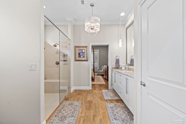 full bathroom featuring a stall shower, connected bathroom, wood finished floors, crown molding, and vanity