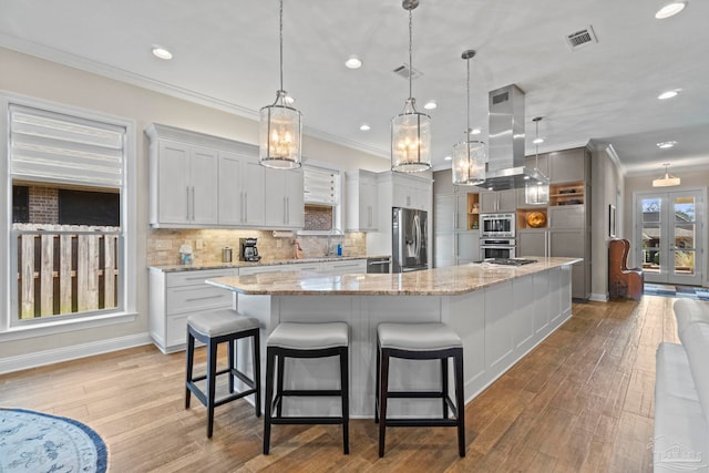 kitchen featuring crown molding, island exhaust hood, a large island, stainless steel appliances, and a sink