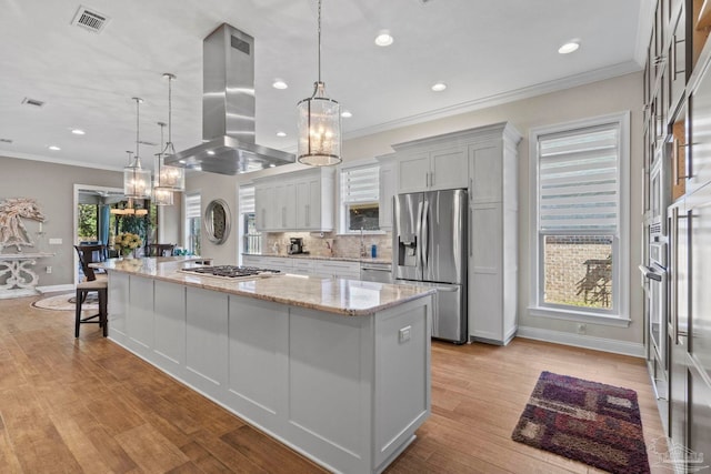 kitchen featuring visible vents, a spacious island, light stone countertops, island exhaust hood, and stainless steel appliances