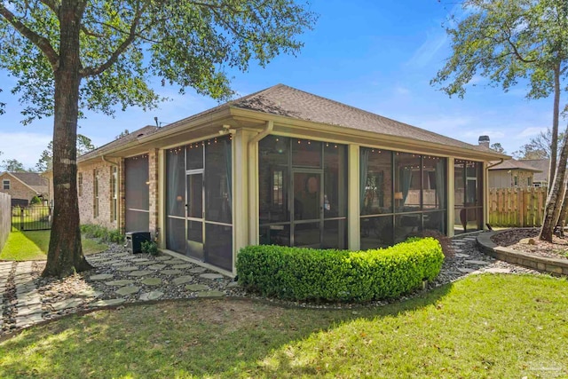 rear view of property featuring a yard, fence, and a sunroom