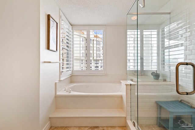 bathroom with plus walk in shower, tile patterned floors, a textured ceiling, and a healthy amount of sunlight