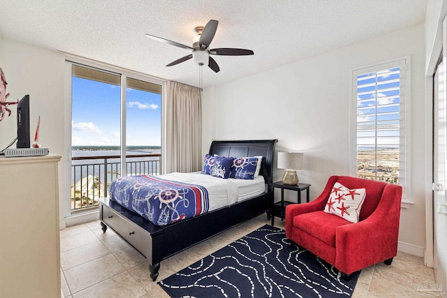 bedroom featuring a textured ceiling, ceiling fan, multiple windows, and access to outside