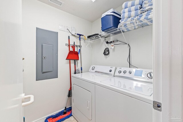 laundry room with electric panel, washing machine and dryer, and a textured ceiling