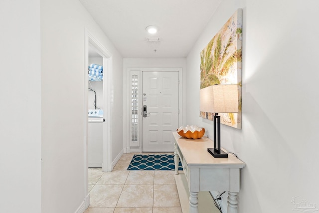 entrance foyer with washer / dryer and light tile patterned floors