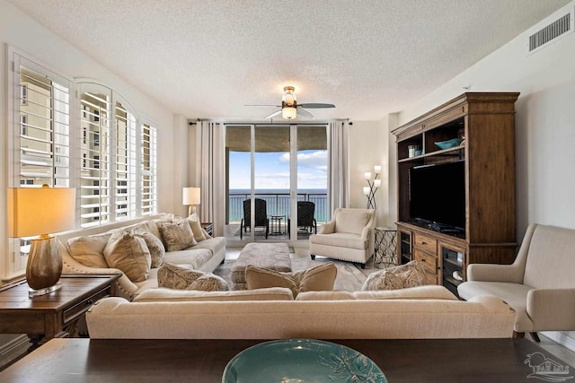 living room featuring a wealth of natural light, ceiling fan, and a textured ceiling