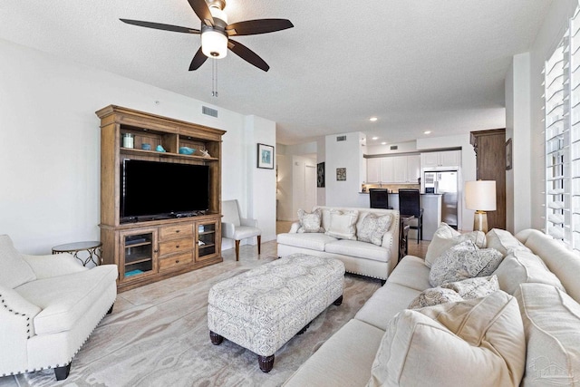 living room with a textured ceiling and ceiling fan