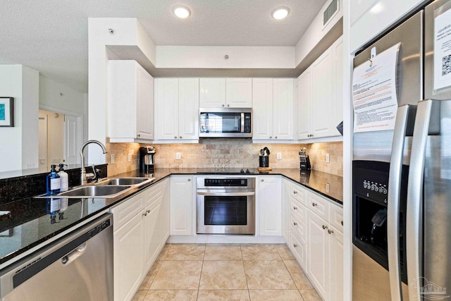 kitchen featuring a textured ceiling, light tile patterned floors, appliances with stainless steel finishes, sink, and white cabinetry