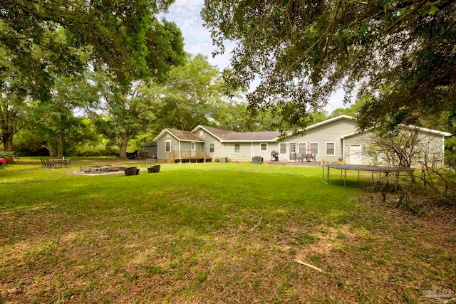 14574 N County Rd 65, Foley, AL 36535 - view of grassy yard featuring a trampoline, an outdoor fire pit, and a wooden deck