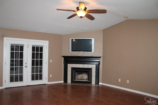 unfurnished living room featuring vaulted ceiling, a fireplace, french doors, dark wood-type flooring, and ceiling fan