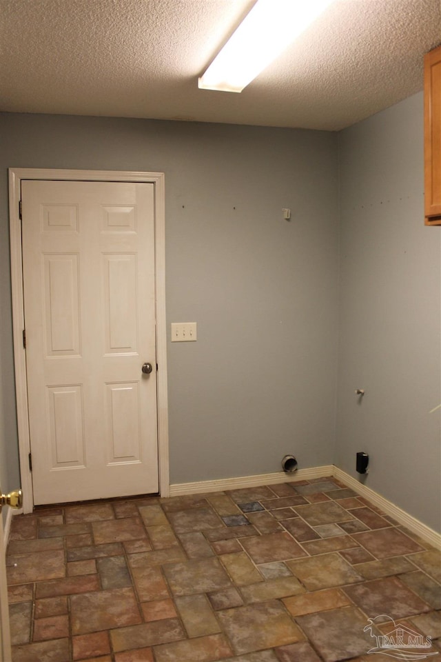 clothes washing area with cabinets and a textured ceiling