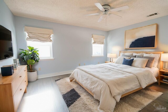 bedroom with hardwood / wood-style flooring, ceiling fan, and a textured ceiling