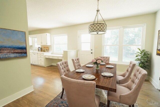 dining area with light wood-type flooring, a wealth of natural light, and a textured ceiling