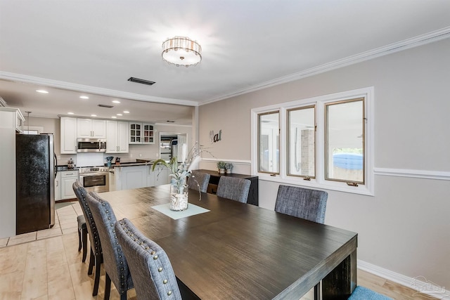 dining area with crown molding and light hardwood / wood-style floors