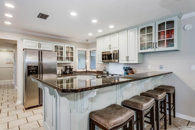 kitchen featuring kitchen peninsula, appliances with stainless steel finishes, white cabinetry, and a breakfast bar area