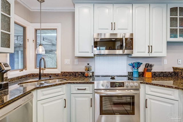 kitchen featuring stainless steel appliances, sink, dark stone countertops, white cabinets, and hanging light fixtures