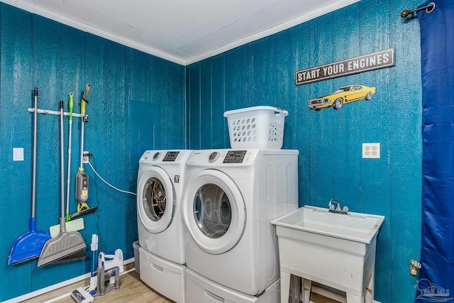 laundry area featuring hardwood / wood-style flooring, washer and clothes dryer, sink, and ornamental molding