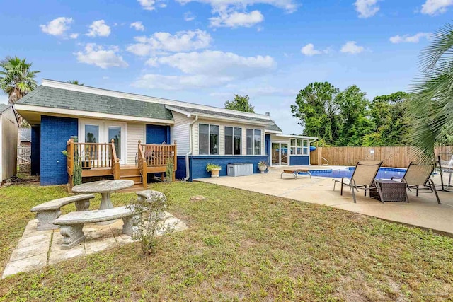 rear view of house with french doors, a patio, a pool side deck, and a lawn