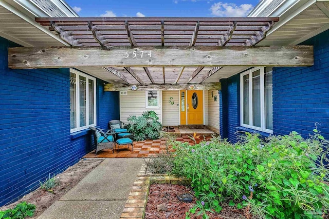 view of exterior entry with a pergola