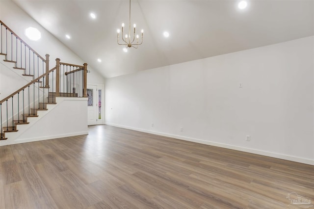 unfurnished living room with baseboards, high vaulted ceiling, stairs, and wood finished floors
