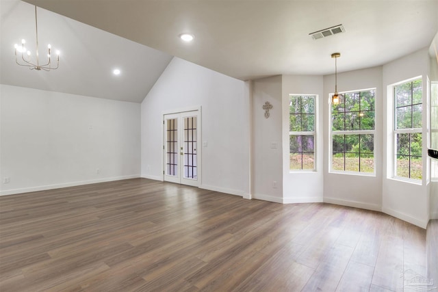 empty room with a chandelier, visible vents, wood finished floors, baseboards, and lofted ceiling