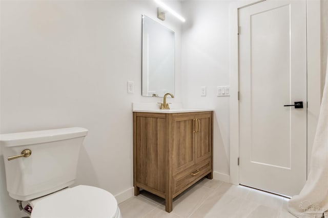 bathroom with baseboards, tile patterned flooring, toilet, and vanity