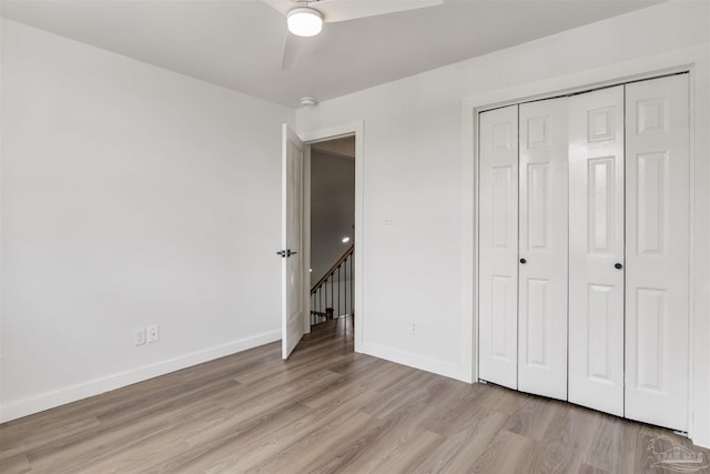 unfurnished bedroom featuring baseboards, ceiling fan, a closet, and light wood finished floors