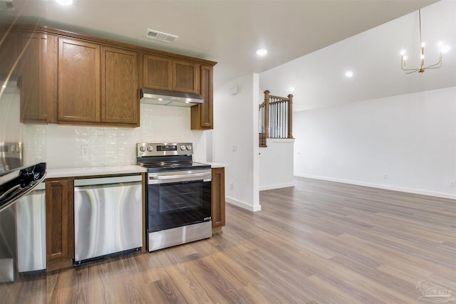 kitchen with visible vents, wood finished floors, light countertops, under cabinet range hood, and stainless steel appliances