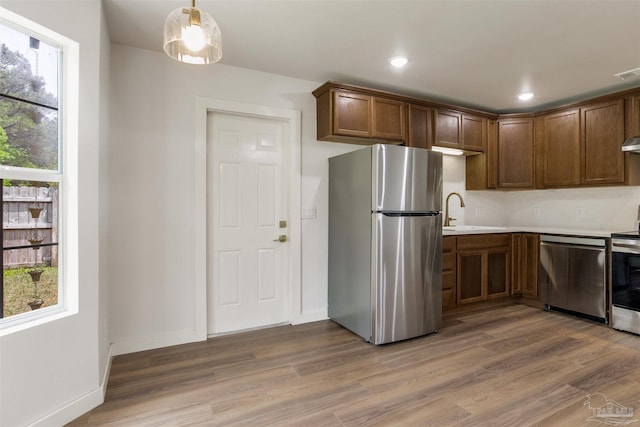 kitchen with a healthy amount of sunlight, light countertops, a sink, light wood finished floors, and appliances with stainless steel finishes