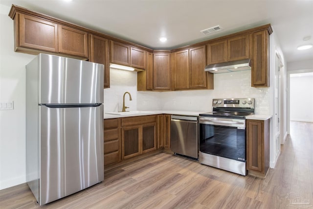 kitchen with visible vents, light wood-type flooring, under cabinet range hood, a sink, and appliances with stainless steel finishes