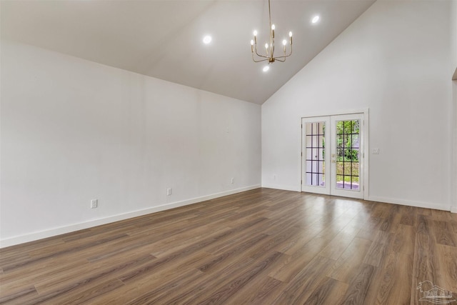 spare room with high vaulted ceiling, baseboards, wood finished floors, and a notable chandelier