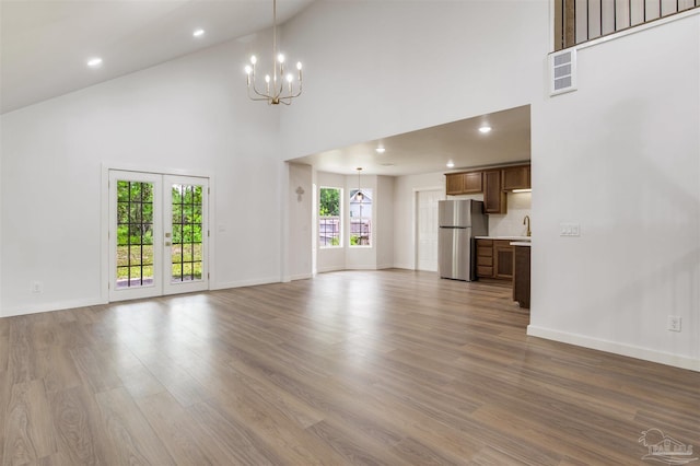 unfurnished living room with an inviting chandelier, baseboards, dark wood-style floors, and high vaulted ceiling