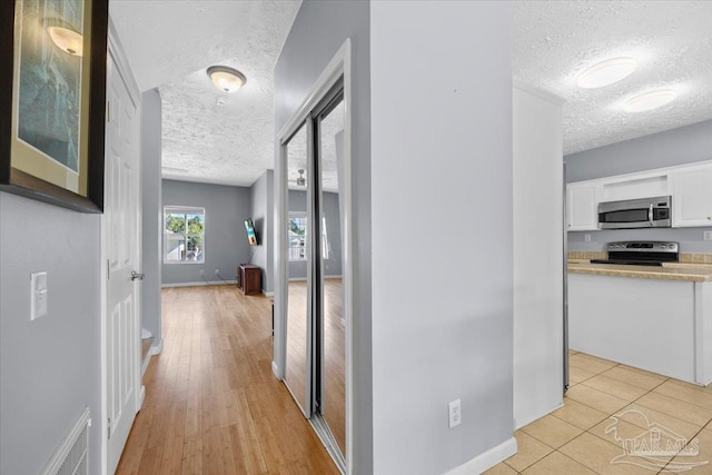 hallway featuring light hardwood / wood-style floors and a textured ceiling