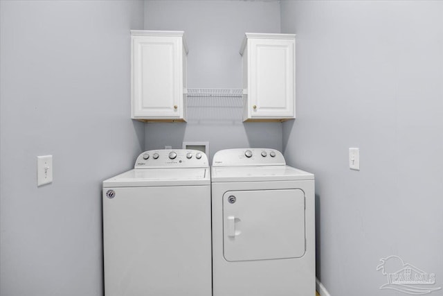 clothes washing area featuring cabinets and washer and clothes dryer