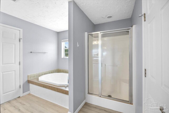 bathroom with independent shower and bath, a textured ceiling, and hardwood / wood-style flooring