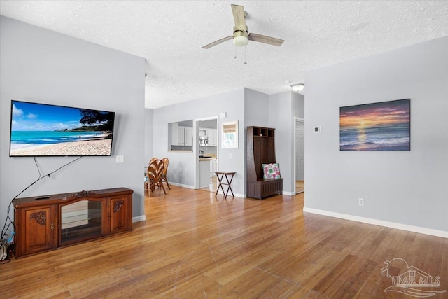 unfurnished living room with ceiling fan, light hardwood / wood-style floors, and a textured ceiling