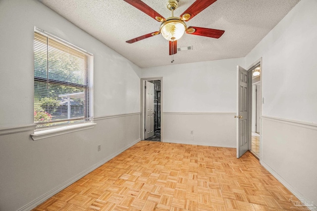 unfurnished room featuring a textured ceiling, visible vents, baseboards, and ceiling fan