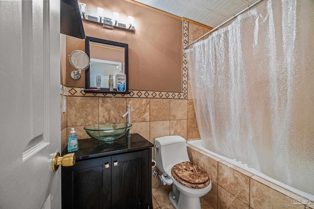 bathroom featuring tile walls, toilet, tiled shower / bath combo, and vanity