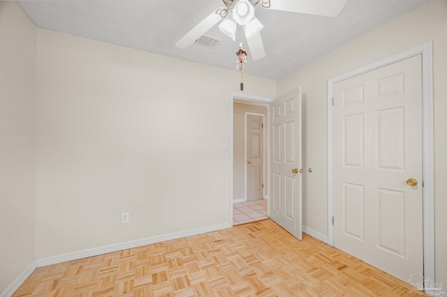 empty room featuring a textured ceiling, baseboards, a ceiling fan, and visible vents
