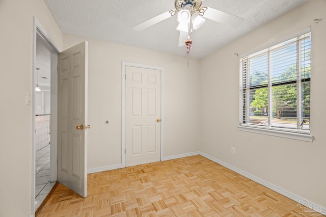 unfurnished bedroom featuring a textured ceiling, baseboards, and a ceiling fan