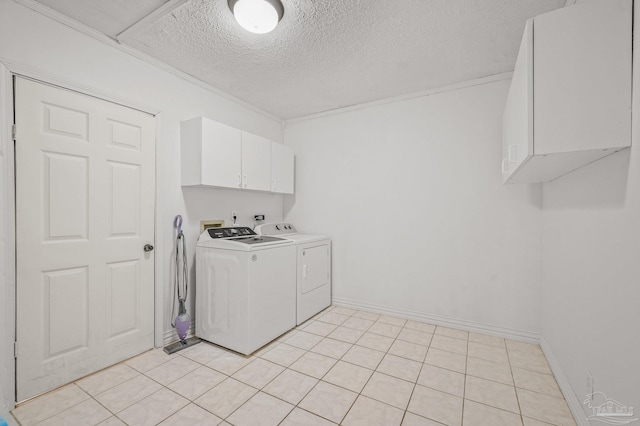 laundry area featuring separate washer and dryer, a textured ceiling, cabinet space, and light tile patterned floors