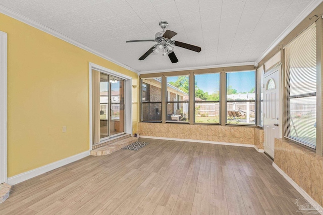 unfurnished sunroom featuring ornamental molding, plenty of natural light, hardwood / wood-style floors, and a ceiling fan