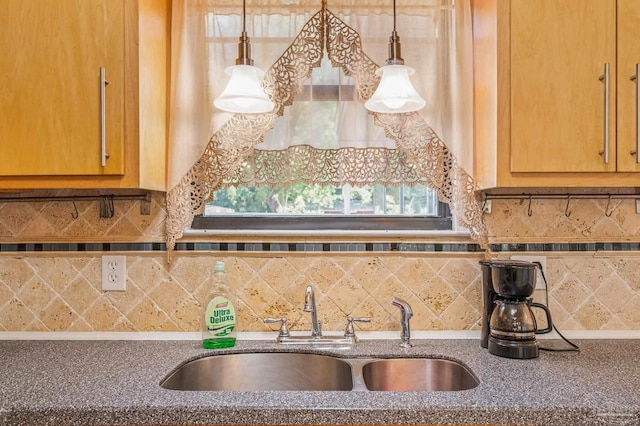 kitchen with decorative light fixtures, dark stone countertops, decorative backsplash, and a sink