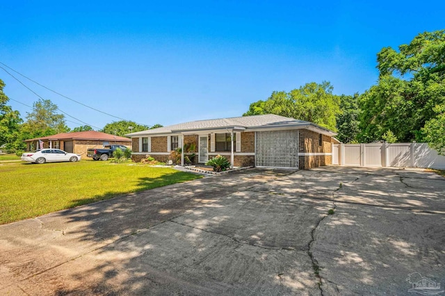 ranch-style home featuring a gate, fence, a front lawn, brick siding, and driveway