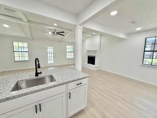 kitchen featuring a wealth of natural light, light wood-type flooring, visible vents, a sink, and open floor plan