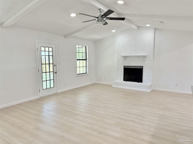 unfurnished living room featuring a brick fireplace, light wood-style floors, a textured ceiling, and ceiling fan