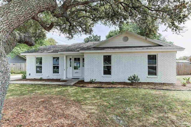 ranch-style house featuring a front yard, fence, and brick siding