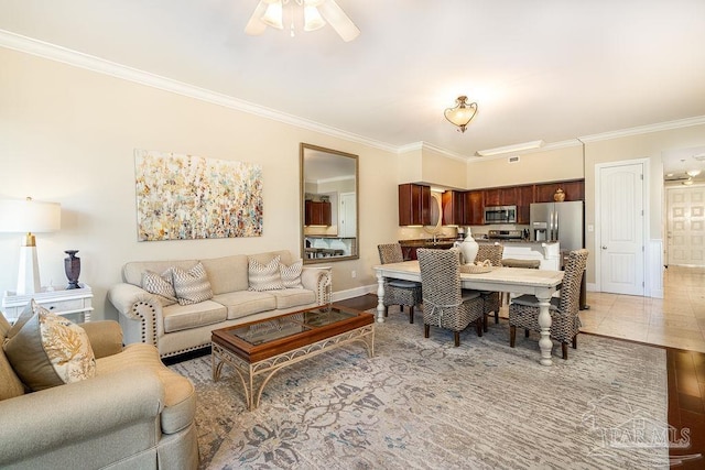 living room with ceiling fan, ornamental molding, light tile patterned flooring, and baseboards